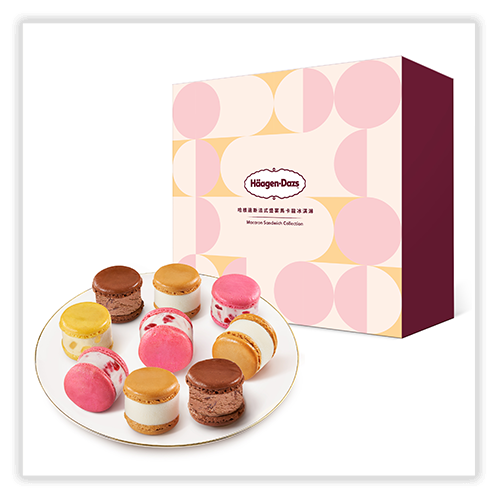 A plate of assorted Häagen-Dazs macaron ice cream sandwiches placed in front of a decorative box with a geometric design in pink, peach, and burgundy. The box features the Häagen-Dazs logo and the text "Macaron Sandwich Collection" in English and Chinese.